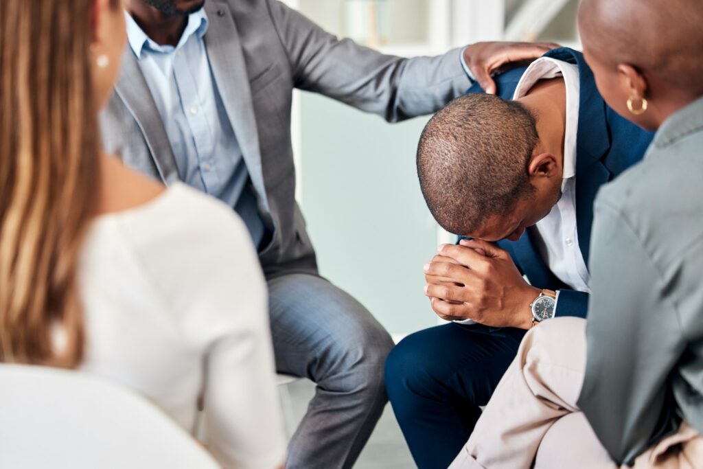 Group therapy, support and counseling with a business man and team in a meeting for emotions or hea